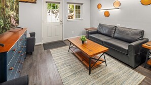 Uma sala de estar moderna com um sofá de couro preto, mesa de centro de madeira e um armário azul.