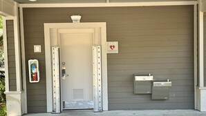 A building entrance with a door, AED sign, fire extinguisher, and utility boxes.