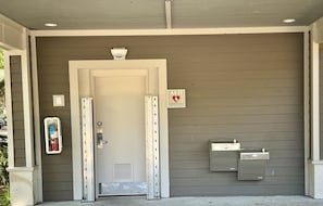 Entrada de edifício com porta, sinal de AED, extintor de incêndio e caixas de utilidades.