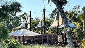 A wooden pirate-themed play area with rope bridges and a slide.