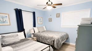 Un dormitorio con dos camas, un ventilador de techo y un aparador.