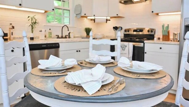 A modern kitchen with white cabinets, a round dining table with placemats, and a central white chair. - Relax at The Blue Bird - 2BD/2BA + Easy Parking (Good Hope)