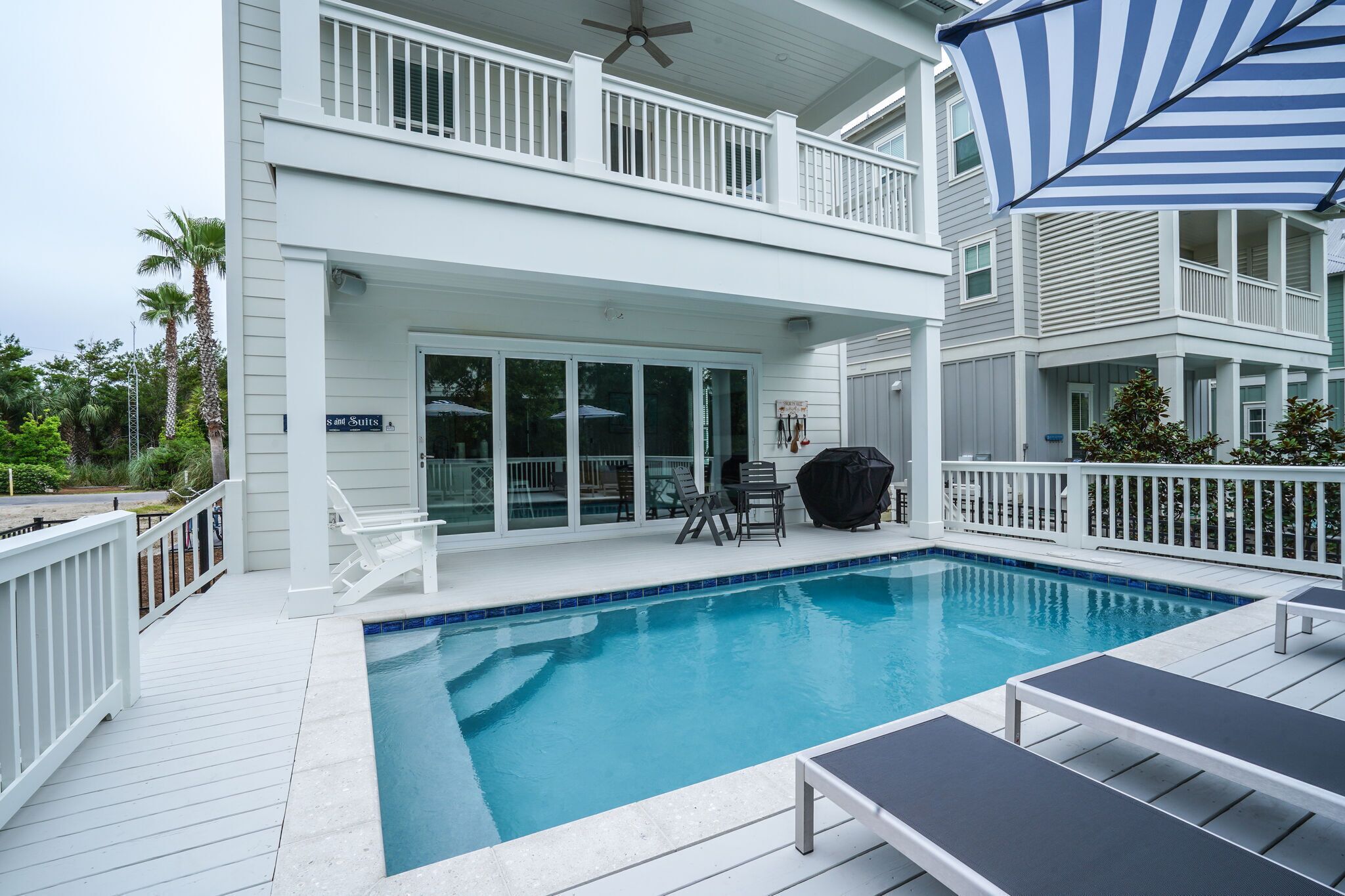 A two-story house with a swimming pool, a covered patio, and a barbecue area.