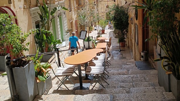 A narrow street with outdoor seating, potted plants, and traditional architecture. - Charming & traditional apartment in Valletta ESCH2 (Valletta)
