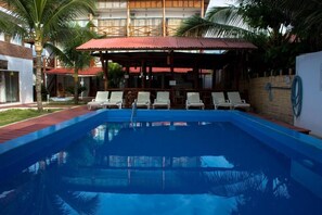 Una piscina al aire libre, sombrillas, sillones reclinables de piscina