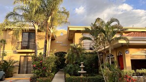 A two-story building with balconies, a garden with a fountain, and a sign reading "Monte Carlo". - Second floor Condo- Great views! a relaxing Paradise in Jaco Beach.  (Jacó)