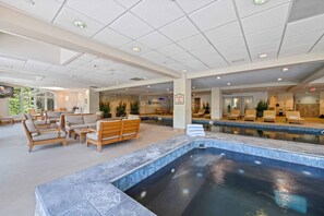 Uma área ampla com piscina interna, cadeiras de lounge e um espaço para sentar.