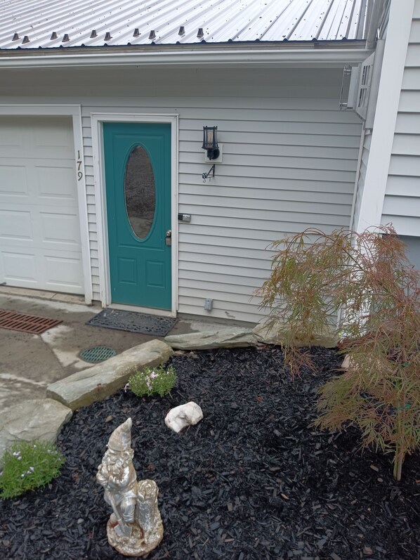 A house with a teal door, a mailbox, and a small garden with mulch, rocks, and a gnome statue. - Central to VT skiing areas 5 minutes to I-89 , near VAST trails, near Norwich (Williamstown)