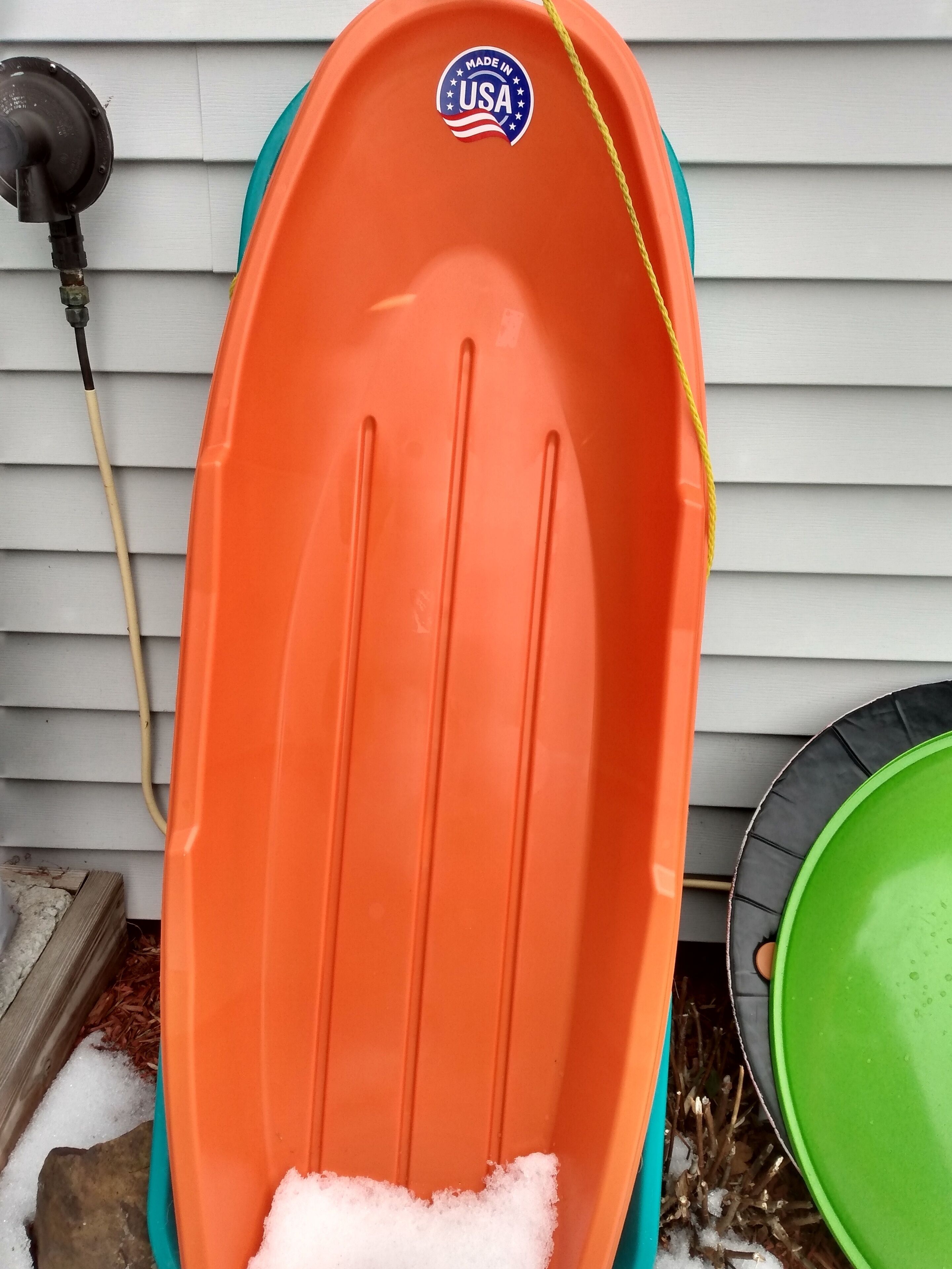 Ein orangefarbenes Schneemobil mit amerikanischem Aufkleber, einem grünen Sitz und einem schwarzen Griff.