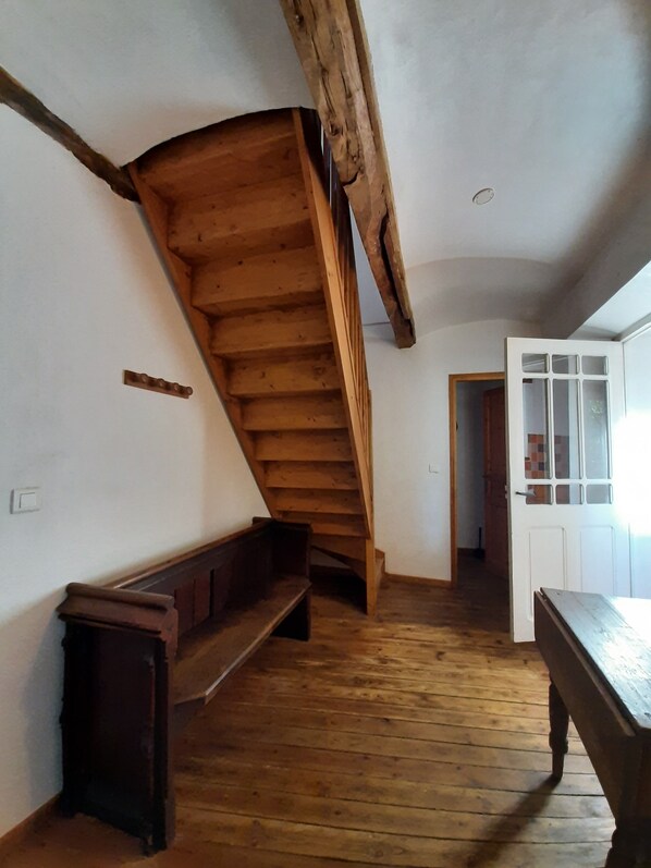 A room with a wooden staircase, a bench, a door with glass panels, and a wooden floor. - Spacious, family-run vacation rental “Roses” – Peace and quiet, a chance to unwind, in the Cèze Valley near the Ardèche (Saint-André-de-Roquepertuis)