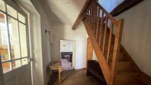 Un escalier en bois menant à un deuxième étage, une table en bois dans le couloir et une porte avec une fenêtre.