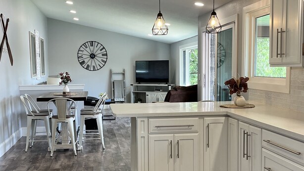 A modern kitchen with white cabinetry, a central island, and pendant lighting. - Serenity awaits at this secluded riverfront property (Muscoda)