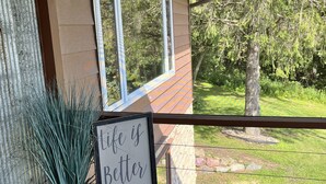 A house with a balcony, a potted plant, and a sign that reads "Life is Better at the River". - Serenity awaits at this secluded riverfront property (Muscoda)