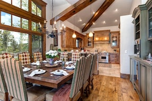 Enjoy meals in this dining area with a large table and comfortable chairs, surrounded by exposed beams and a chandelier.