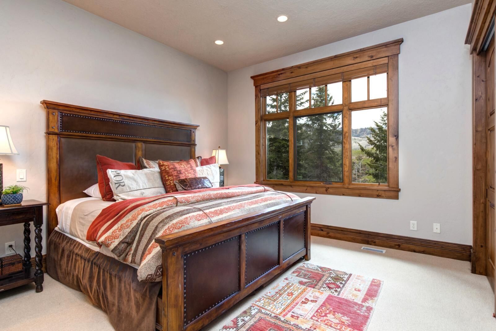 A bedroom with a large bed, a window, and a wooden headboard.