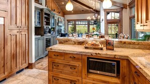 Una cocina con gabinetes de madera, encimera de granito y microondas integrado.