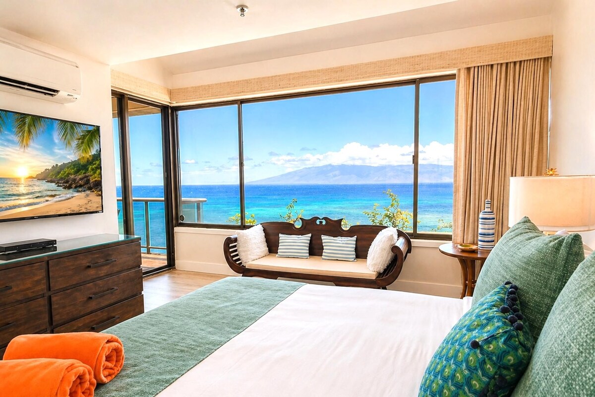 A hotel room with a large window, a bed, a sofa, a TV, and a dresser.