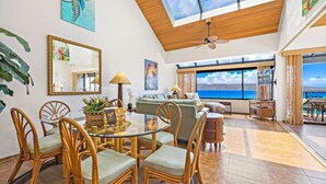 A spacious living area with a dining table, chairs, a sofa, and a view of the ocean.