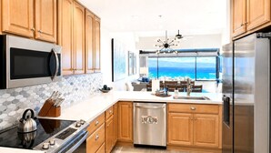 A modern kitchen with wooden cabinets, stainless steel appliances, and a view of the ocean.