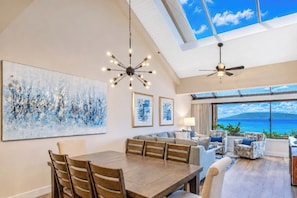 A spacious dining area with a high ceiling, a large painting, and a view of the ocean. - Sands of Kahana Resort by KBM (Lahaina)