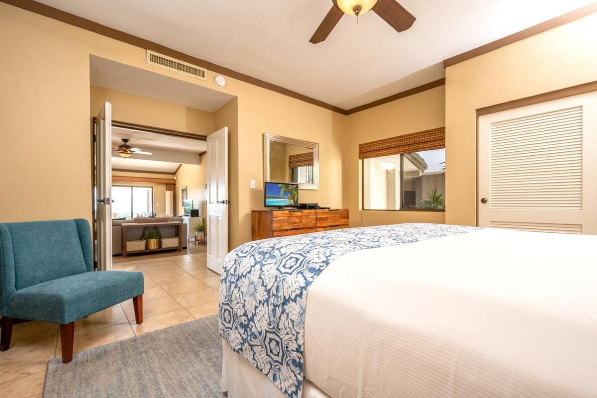 A bedroom with a large bed, a TV, a desk, and a chair.