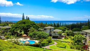 Un resort con piscina, abundante vegetación y vistas al océano.