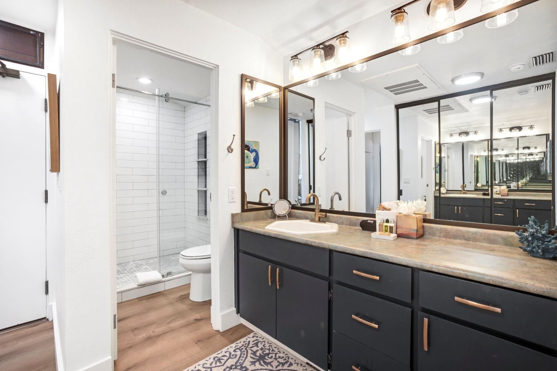 A modern bathroom with a large mirror, a sink, and a shower.