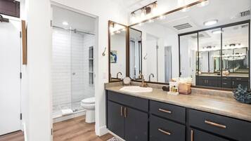 A modern bathroom with a large mirror, a sink, and a shower.
