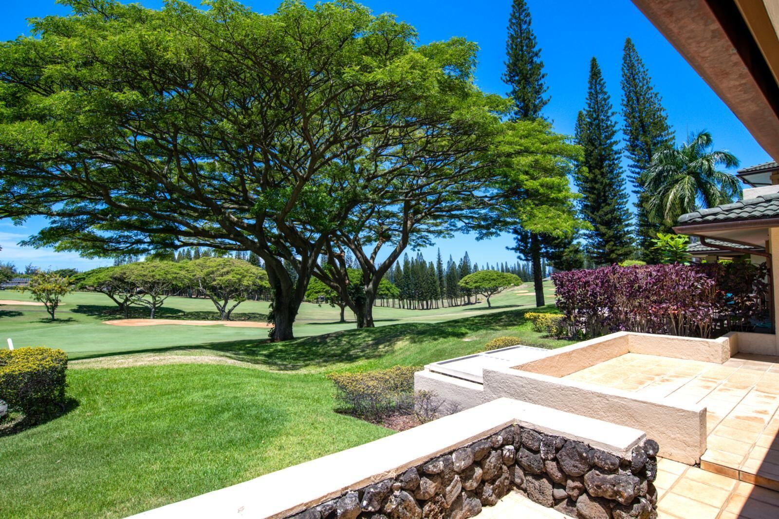 A golf course with a stone retaining wall and a patio area.