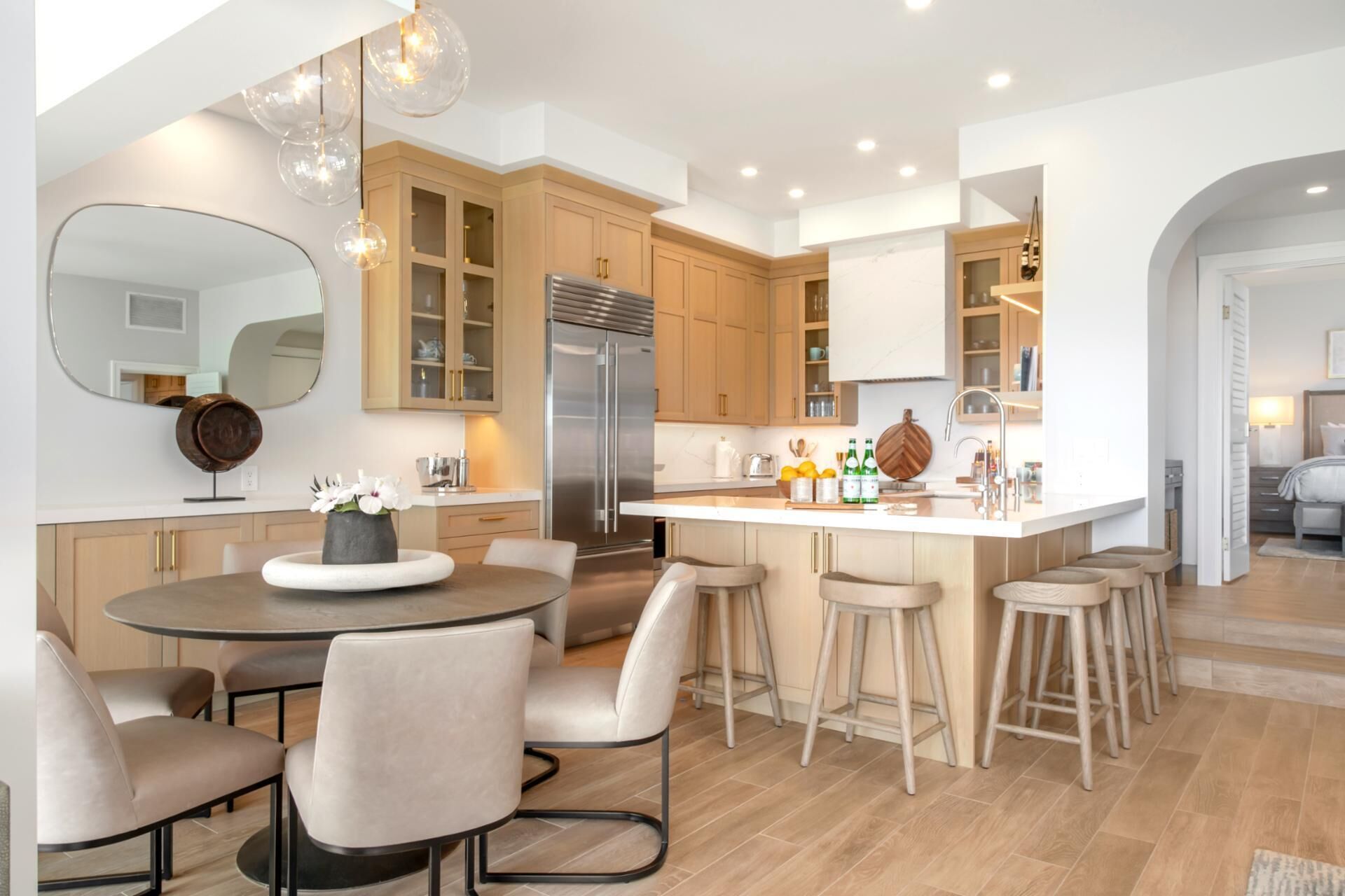 A modern kitchen with a central island, bar stools, and a dining area with a round table and chairs.