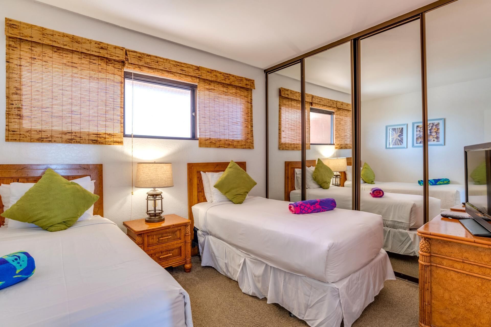 A hotel room with two beds, a large mirror, and a television.