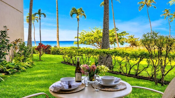 A table set outdoors with a view of the ocean and palm trees. - Kaanapali Shores Resort by KBM (Lahaina)