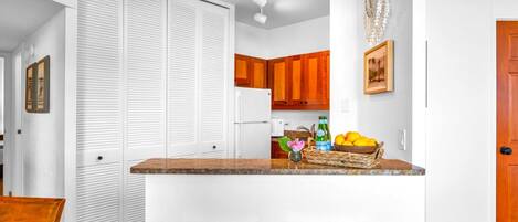 A kitchen with wooden cabinets, a white countertop, and two wooden stools.