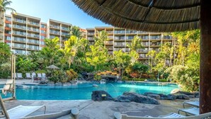 A resort with a pool surrounded by palm trees and a thatched roof structure. - Kaanapali Shores Resort by KBM (Lahaina)
