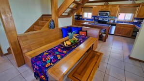 A wooden staircase leading to a dining area with a bench and a table set with fruits and a colorful tablecloth. - Incredible Ocean views from both sides of this hill top home. (Roatan)
