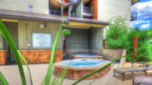 Ein Wellnessbereich mit zwei Whirlpools, einer Holzterrasse und einer Steinwand.