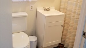 Een kleine, schone badkamer met toilet, wastafel en douchegordijn.