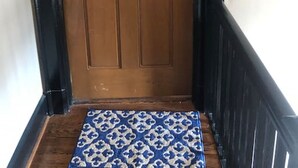 A wooden door with a brass doorknob and a small brass plate above it.