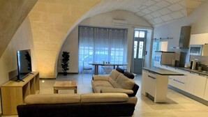Een moderne woonkamer met een bank, een bijzettafeltje en een televisie op een houten dressoir.