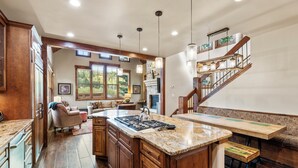 Un'ampia cucina con mobili in legno, una grande isola e una scala che conduce a un piano superiore.