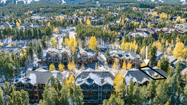 Ett semesterområde med flera byggnader, omgivet av träd och berg.