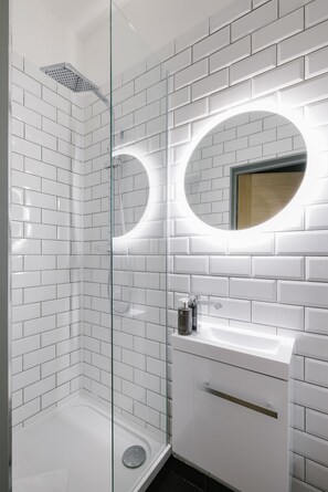 Enjoy a refreshing shower in the sleek bathroom with a glass-enclosed shower and modern sink area.