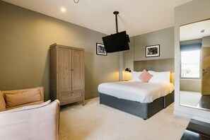 Relax in this serene bedroom with a large bed, wardrobe, and armchair.