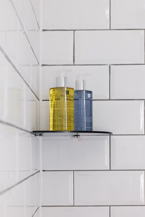 Bathroom features a bathtub and a wall-mounted shelf with toiletry storage.
