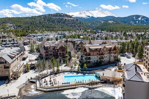 A resort area with a large pool, multiple buildings, and a mountain backdrop. - Close to Peak 9, On Main St, Shared Pool/Hot Tubs. (Breckenridge)