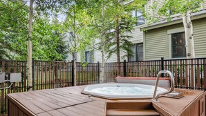 A wooden hot tub with steps and a metal ladder, surrounded by a wooden deck and a black metal fence. - Close to Peak 9, On Main St, Shared Pool/Hot Tubs. (Breckenridge)