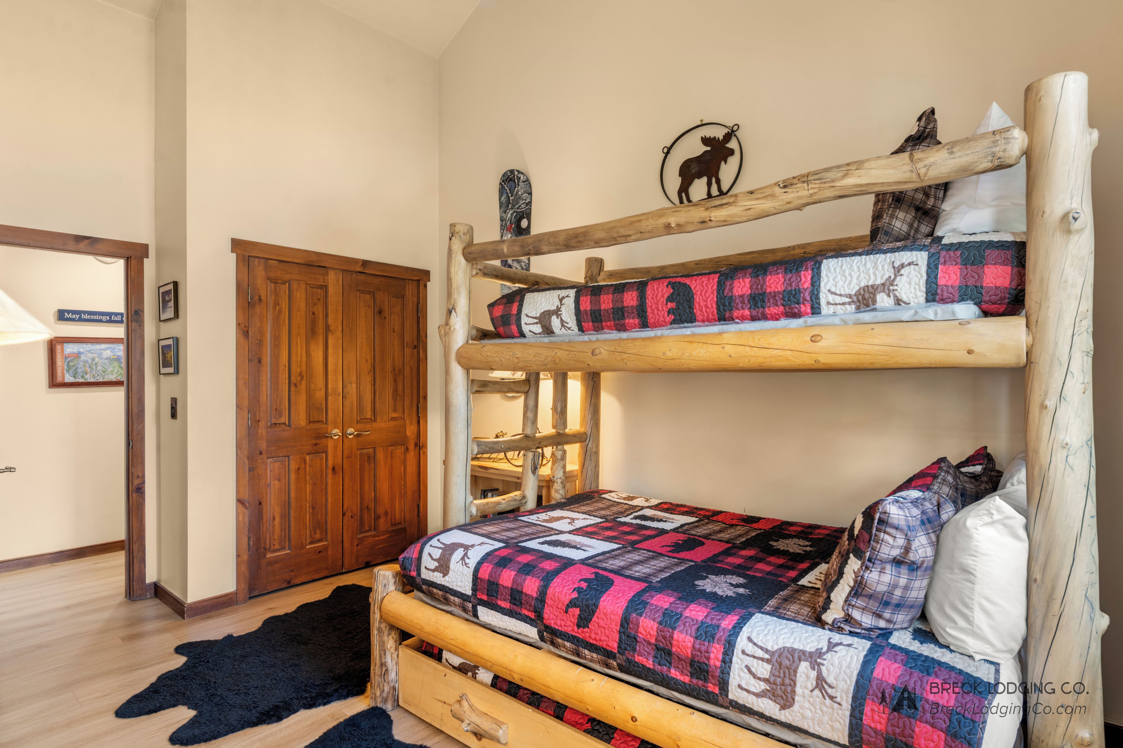 Un lit superposé avec une courtepointe ornée de motifs animaliers, une porte en bois et un tapis noir.
