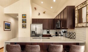 Una cocina moderna con una isla grande, electrodomésticos de acero inoxidable y armarios de madera oscura.
