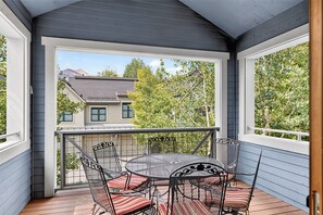 A covered outdoor seating area with a table and chairs, overlooking a residential neighborhood.