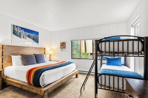 A bunk bed room with a wooden headboard, a large window, and a framed picture on the wall. - Newly Remodeled/Furnished at Peak 9 Base/Downtown (Breckenridge)